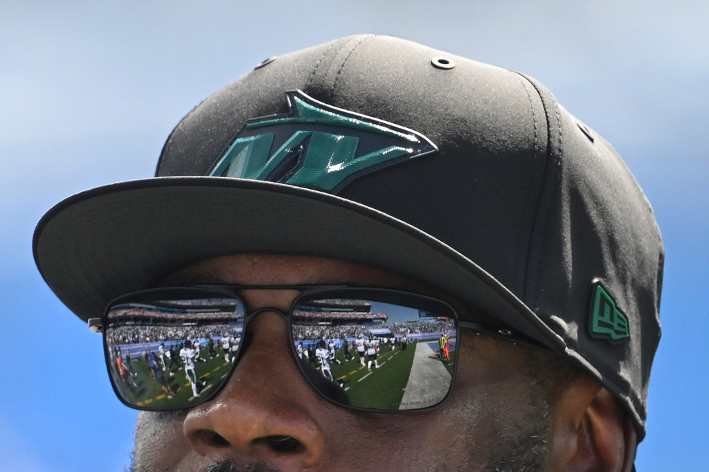 New York Jets players leaving the field are reflected in the sunglasses of head coach Aaron Glenn, at the end of the first half of an NFL football game against the Tennessee Titans, Sunday, Sept. 13, 2026, in Nashville, Tenn. (AP Photo/John Amis)