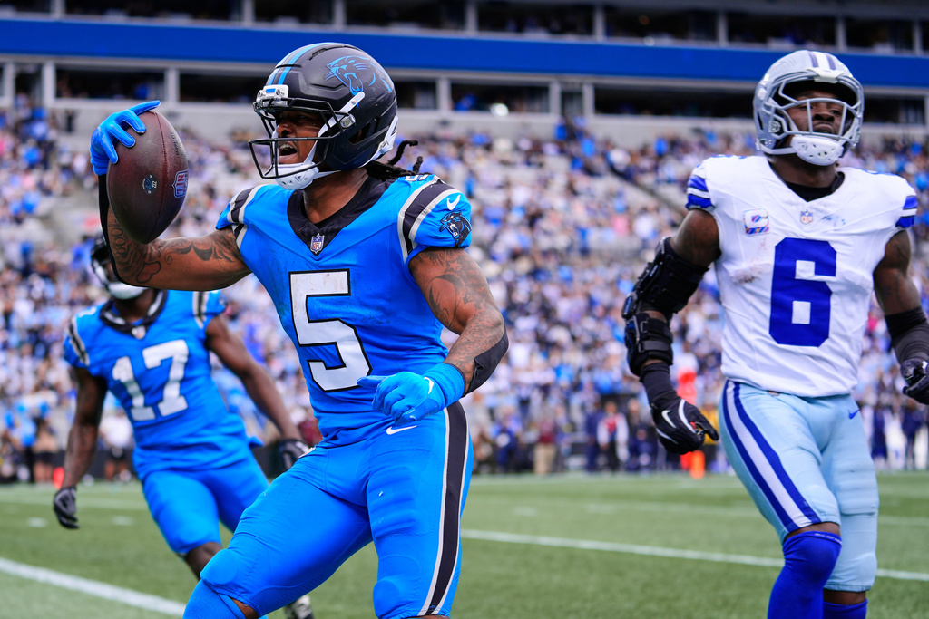 Carolina Panthers' Rico Dowdle (5) celebrates his touchdown run in front of Dallas Cowboys' Donovan Wilson (6) in the second half of an NFL football game, Sunday, Oct. 12, 2025, in Charlotte, N.C. (AP Photo/Erik Verduzco)