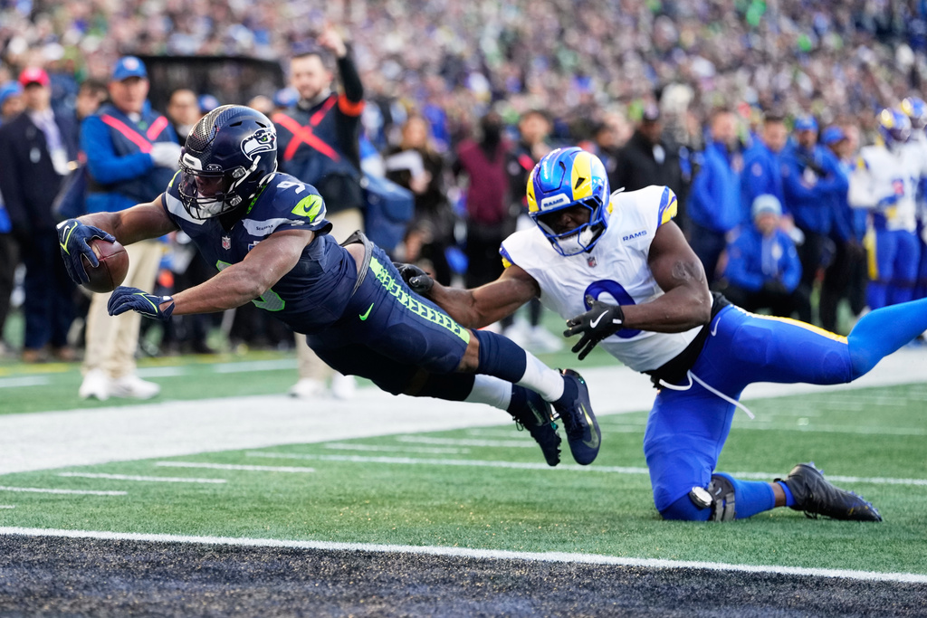 Seattle Seahawks running back Kenneth Walker III (9) scores a touchdown past Los Angeles Rams linebacker Byron Young (0) during the first half of the NFC Championship NFL football game Sunday, Jan. 25, 2026, in Seattle. (AP Photo/Stephen Brashear)