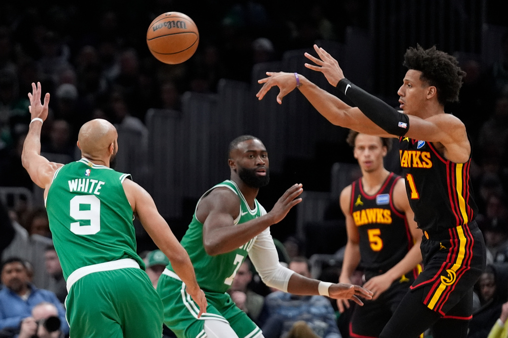 Atlanta Hawks forward Jalen Johnson (1) passes over Boston Celtics guard Derrick White (9) during the first half of an NBA basketball game, Wednesday, Jan. 28, 2026, in Boston. (AP Photo/Robert F. Bukaty)