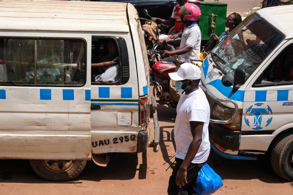 A man wearing a protective mask walks along a busy street in Kampala, Uganda, Tuesday, May 19, 2026. (AP Photo/Hajarah Nalwadda)