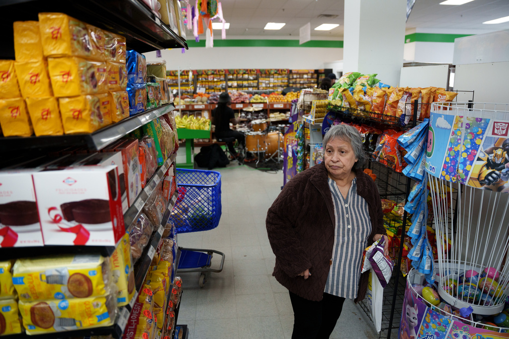 A woman shops while a band plays in the background in New Castle, Del., on Sunday, April 26, 2026. (AP Photo/Mingson Lau)