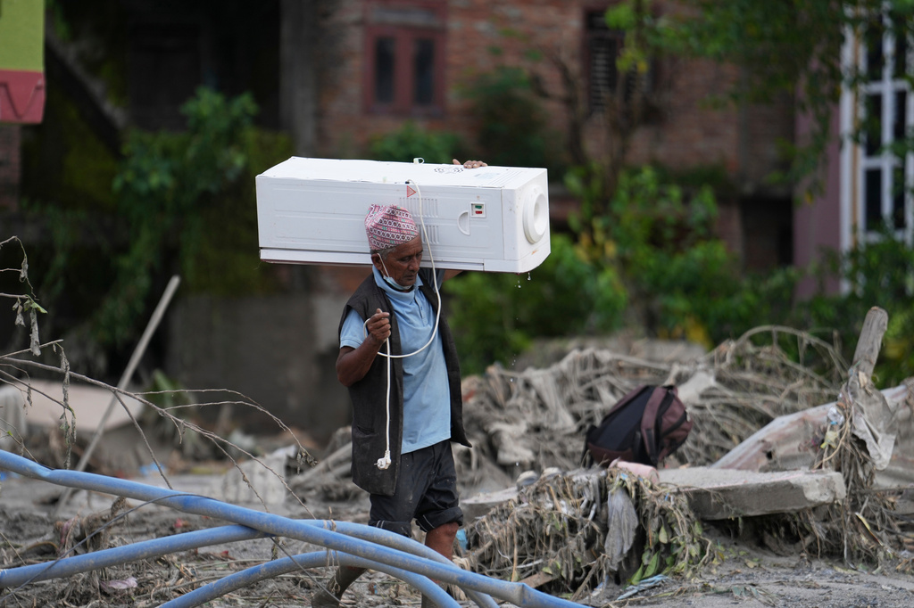 A resident carries an air cooler salvaged from his damaged house after flash flooding in the Devighat area of Nuwakot district, Nepal, Saturday, Aug. 29, 2026. (AP Photo/Rajesh Kumar Singh)