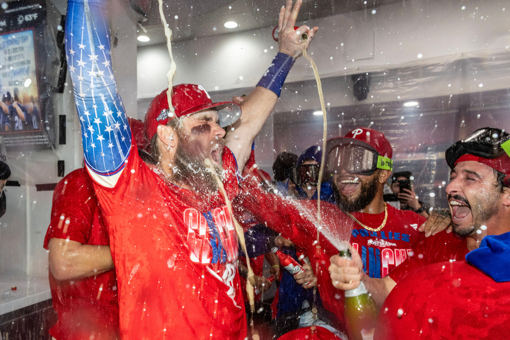 Philadelphia Phillies first baseman Bryce Harper, left, is doused by Garret Stubbs, right, during a celebration in the clubhouse after the team clinched a Wild Card slot in the postseason by defeating the Tampa Bay Rays in a baseball game Sunday, Sept. 27, 2026, in Philadelphia. (AP Photo/Laurence Kesterson)