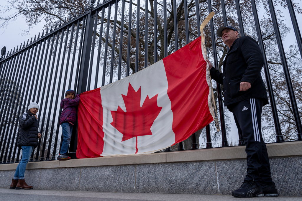 FILE - From right, Toronto residents Douglas Bloomfield, his son Phoenix and wife Ame, who are on vacation in Washington, hold a Canadian flag and an ice hockey stick to show their support for Canada regarding trade tariffs, in front of the White House in Washington, March 13, 2025. (AP Photo/Ben Curtis, File)