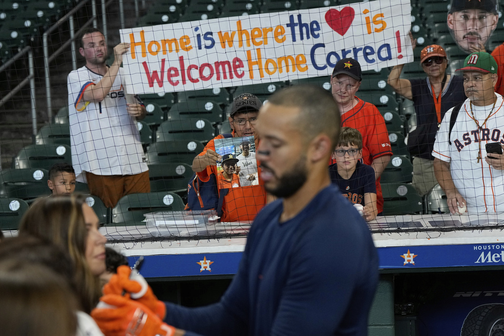 Fans hold a sign as Houston Astros third baseman Carlos Correa signs autographs during batting practice before a baseball game against the Boston Red Sox Monday, Aug. 11, 2025, in Houston. (AP Photo/David J. Phillip)