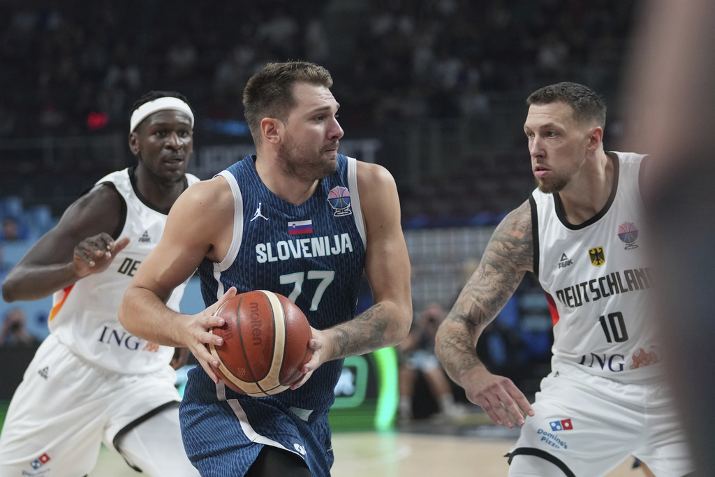 Slovenia's Luka Doncic, centre, Germany's Daniel Theis, right, during the Eurobasket, European Basketball Championship quarter final match between Germany and Slovenia at the Riga Arena in Riga, Latvia, Wednesday, Sept. 10, 2025. (AP Photo/Sergei Grits)