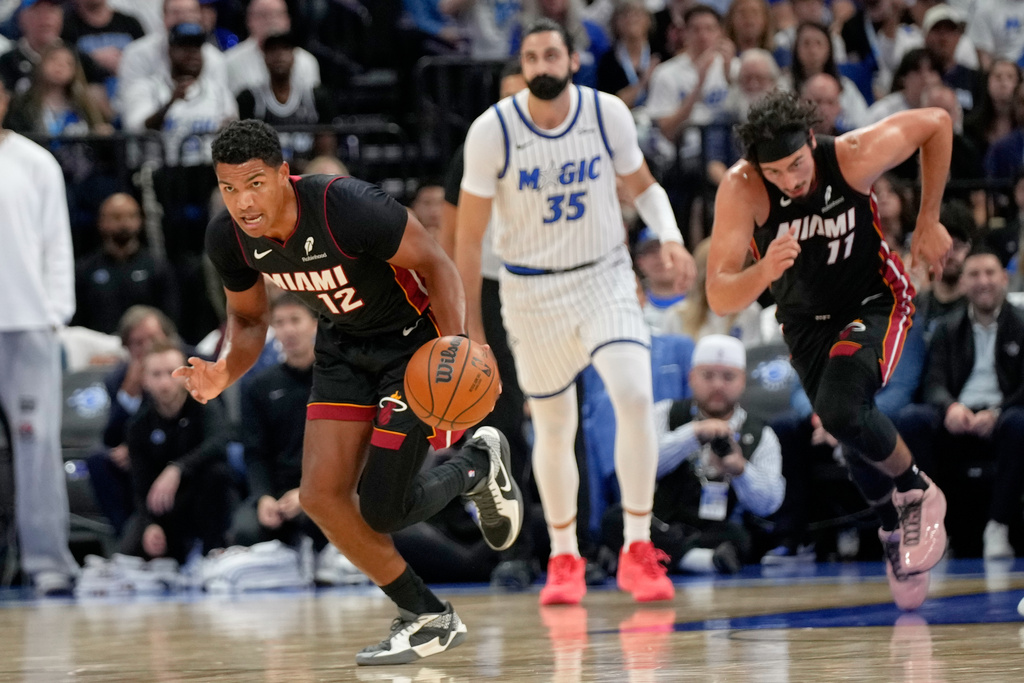 Miami Heat guard Dru Smith (12) takes off on a fast break in front of Orlando Magic center Goga Bitadze (35) during the first half of an NBA basketball game, Wednesday, Oct. 22, 2025, in Orlando, Fla. (AP Photo/John Raoux)