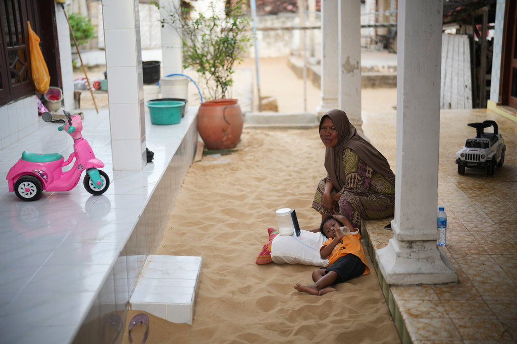A woman looks after her son in a sandpit at home in Legung Timur village in Sumenep on Madura Island, Indonesia, Tuesday, Sept. 9, 2025. (AP Photo/Dita Alangkara)