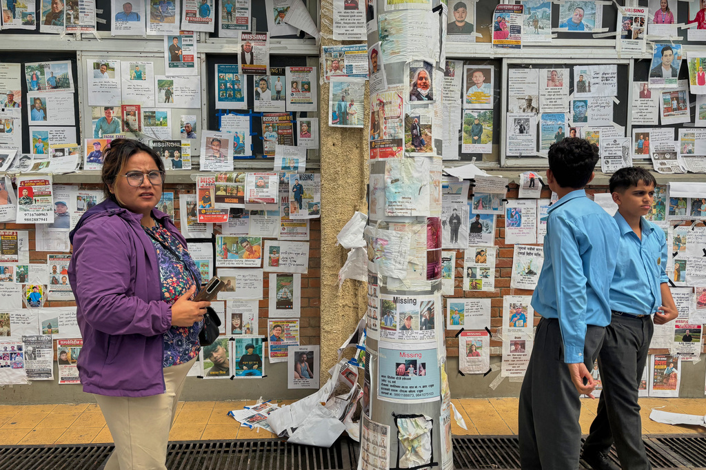 In this photo taken with a smartphone, people look at photographs of hundreds of people missing since last month’s floods, posted on a wall by relatives hoping to receive information about them at Tribhuvan University Teaching Hospital, in Kathmandu, Nepal, Thursday, Sept. 17, 2026. (AP photo/Upendra Man Singh)