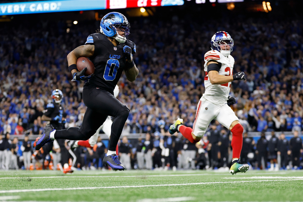 Detroit Lions running back Jahmyr Gibbs (0) runs past New York Giants safety Dane Belton (24) for a touchdown in overtime of an NFL football game in Detroit, Sunday, Nov. 23, 2025. (AP Photo/Rey Del Rio)