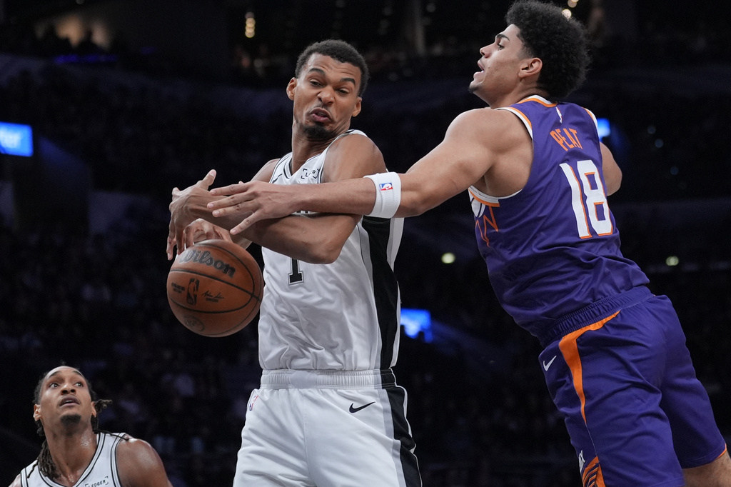 San Antonio Spurs forward Victor Wembanyama (1) and Phoenix Suns forward Koa Peat (18) battle for a rebound during the first half of a preseason NBA basketball game in San Antonio, Wednesday, Oct. 14, 2026. (AP Photo/Eric Gay)