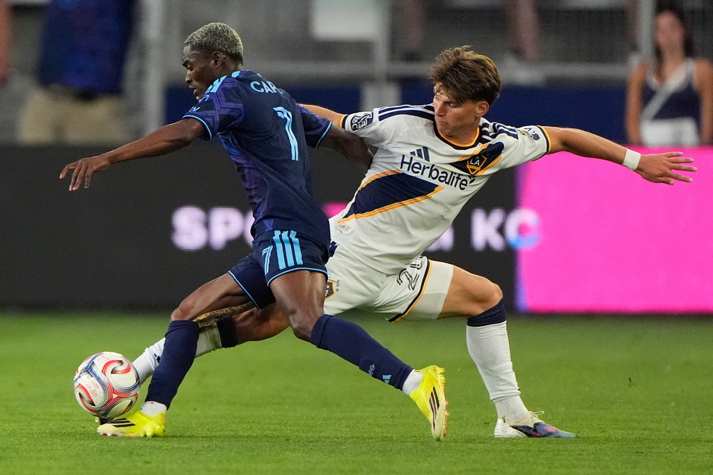 Sporting Kansas City forward Capita (7) and LA Galaxy forward Harbor Miller, right, battle for the ball during the first half of an MLS soccer match Wednesday, May 13, 2026, in Kansas City, Kan. (AP Photo/Charlie Riedel)