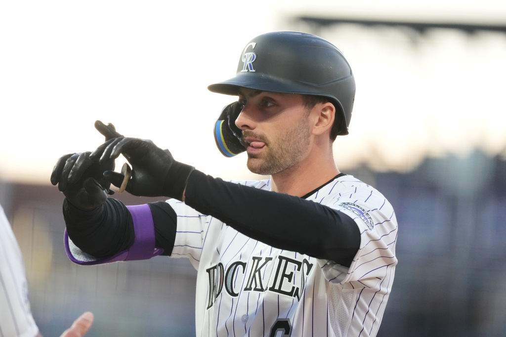 Colorado Rockies' Edouard Julien gestures to the dugout after reaching first base on an RBI single off San Diego Padres starting pitcher Walker Buehler in the second inning of a baseball game Wednesday, April 22, 2026, in Denver. (AP Photo/David Zalubowski)
