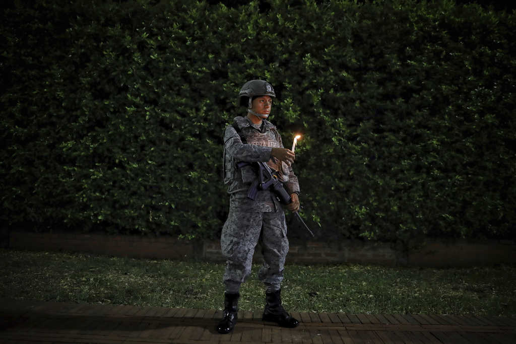 A member of the Air Force holds a candle outside an air base in Cali, Colombia, Sunday, Aug. 24, 2025, during a vigil to honor the victims of a car bomb that exploded there three days earlier. (AP Photo/Santiago Saldarriaga)