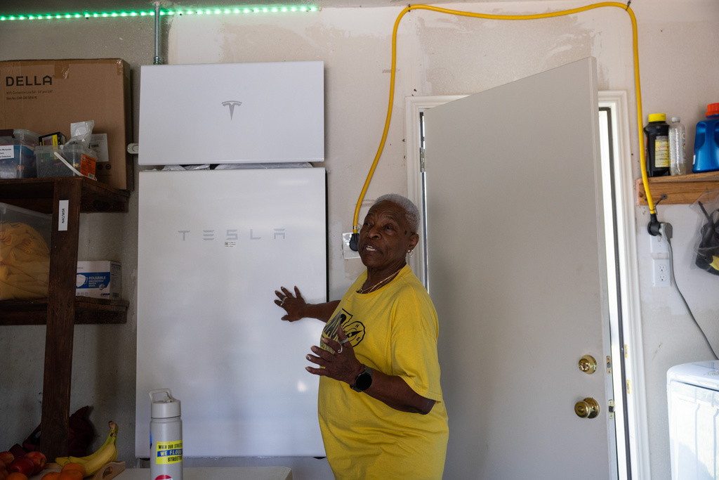 Doris Brown, Hub home captain, gives a tour of her garage and shows a Tesla Powerwall battery that is charged by the solar panels on top of her home, Wednesday, Oct. 8, 2025, in Houston. (AP Photo/Antranik Tavitian)