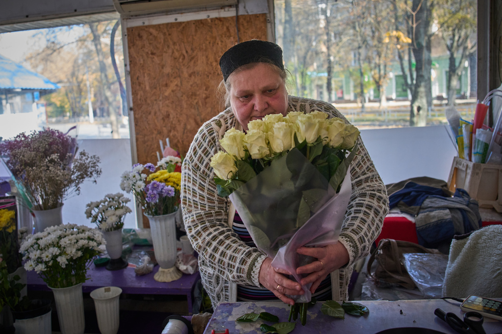 Florist Olha Komanytska, an owner of a small flower kiosk, wraps a rose bouquet in the frontline city of Kherson, Southern Ukraine, Nov. 2, 2025. (AP Photo/Efrem Lukatsky)
