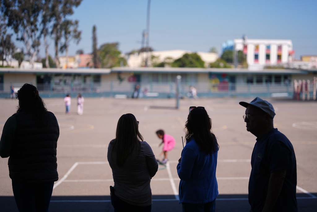 Teachers look on as students play on the playground at Perkins K-8 School Thursday, Nov. 13, 2025, in San Diego. (AP Photo/Gregory Bull)