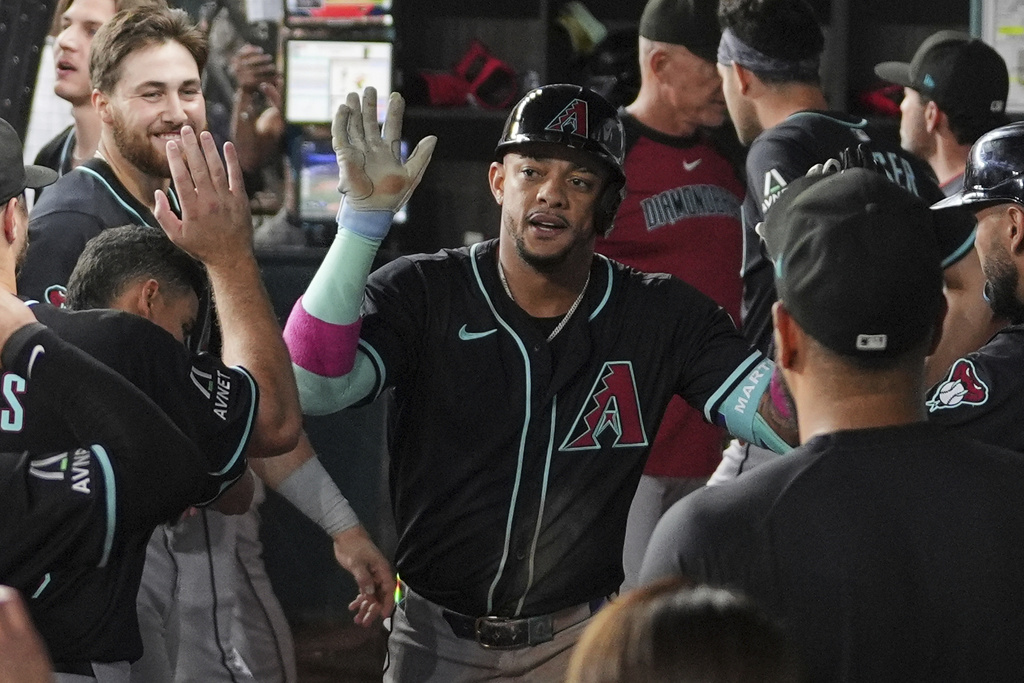 Arizona Diamondbacks second baseman Ketel Marte, center, celebrates in the dugout after hitting a solo home run in the ninth inning of a baseball game against the Texas Rangers Tuesday, Aug. 12, 2025, in Arlington, Texas. (AP Photo/Tony Gutierrez)