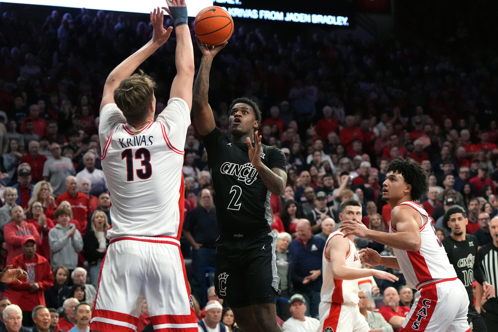 Cincinnati guard Jizzle James drives on Arizona center Motiejus Krivas and guard Brayden Burries (5) during the first half of an NCAA college basketball game, Wednesday, Jan. 21, 2026, in Tucson, Ariz. (AP Photo/Rick Scuteri)