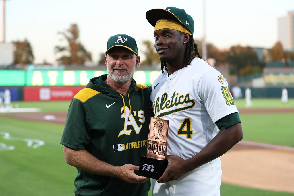Athletics' Lawrence Butler (4) and Manager Mark Kotsay, left, poses as Bulter is honored with being named the Athletics nominee for the Roberto Clemente award before a baseball game against the Houston Astros, Tuesday, Sept. 23, 2025, in West Sacramento, Calif. (AP Photo/Scott Marshall)