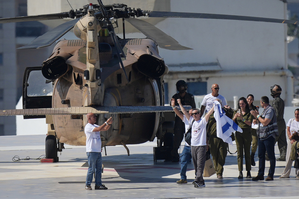 Omri Miran, an Israeli hostage released from the Gaza Strip waves an Israeli flag after coming off a helicopter at the Ichilov Hospital, in Tel Aviv, Israel, Monday, Oct. 13, 2025. (AP Photo/Ohad Zwigenberg)