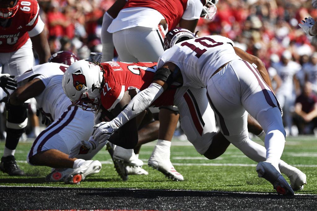 Louisville running back Keyjuan Brown (22) avoids the tackle attempt by Eastern Kentucky defensive back Derek Taylor (10) as he dives over the goal line to score during the first half of an NCAA college football game in Louisville, Ky., Saturday, Aug. 30, 2025. (AP Photo/Timothy D. Easley)