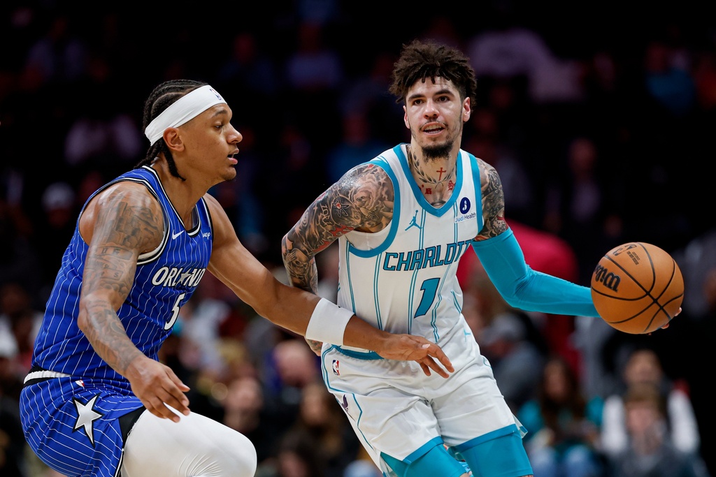Charlotte Hornets guard LaMelo Ball (1) moves the ball against Orlando Magic forward Paolo Banchero, left, during the first half of an NBA basketball game in Charlotte, N.C., Thursday, Oct. 30, 2025. (AP Photo/Nell Redmond)