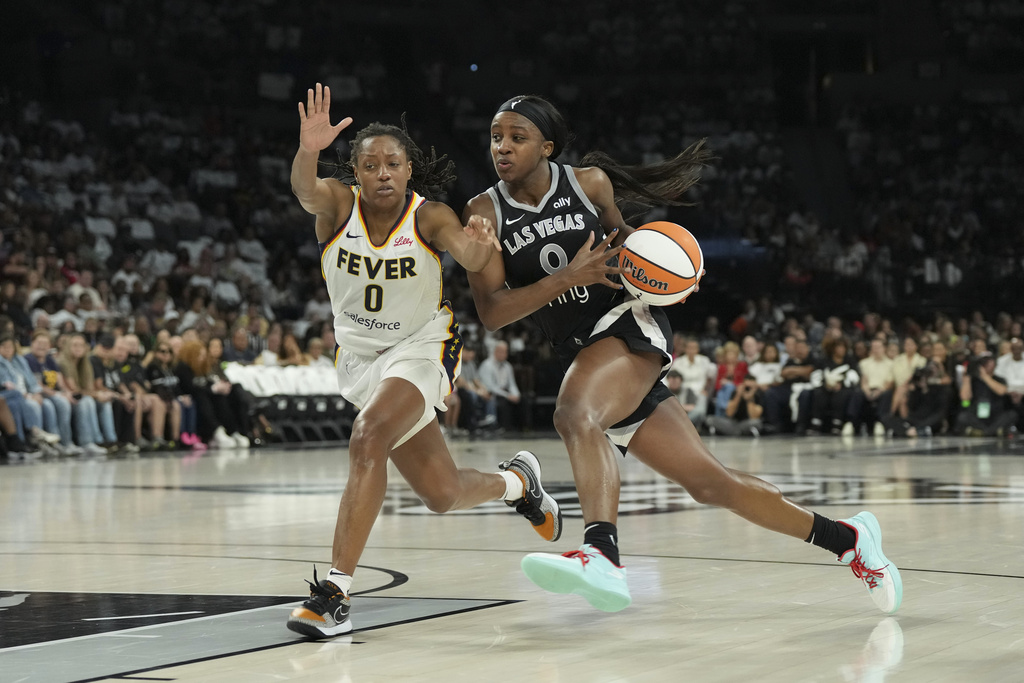 Las Vegas Aces guard Jackie Young, right, drives past Indiana Fever guard Kelsey Mitchell, left, in the first half of Game 1 of a WNBA basketball playoff semifinals series Sunday, Sept. 21, 2025, in Las Vegas. (AP Photo/Candice Ward)