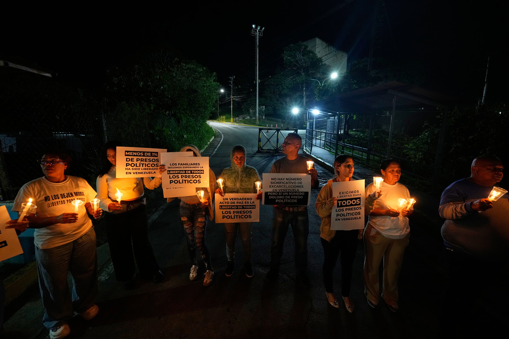 Relatives and friends of political prisoners hold banners and candles calling for their loved ones to be set free outside the Rodeo I prison in Guatire, Venezuela, Friday, Jan. 9, 2026 after the government announced prisoners would be released. (AP Photo/Matias Delacroix)