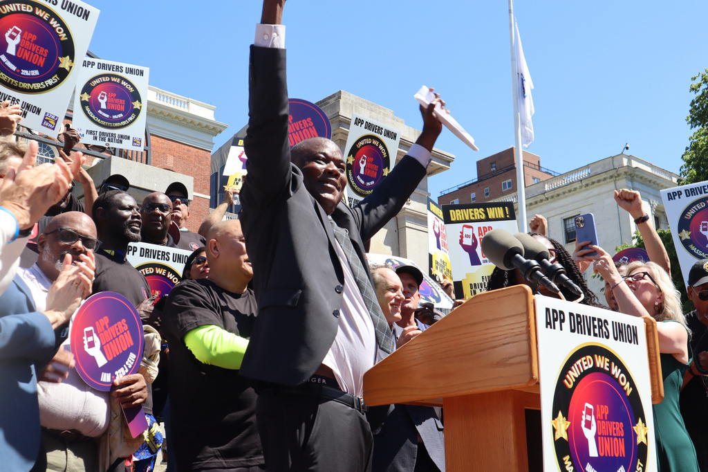 Massachusetts Uber driver Jean Fredo raises his arms while speaking during a during a rally outside the Massachusetts State House after the App Drivers Union announced it had become the first certified union of rideshare drivers in the nation, on Tuesday, May 26, 2026, in Boston. (AP Photo/Leah Willingham)