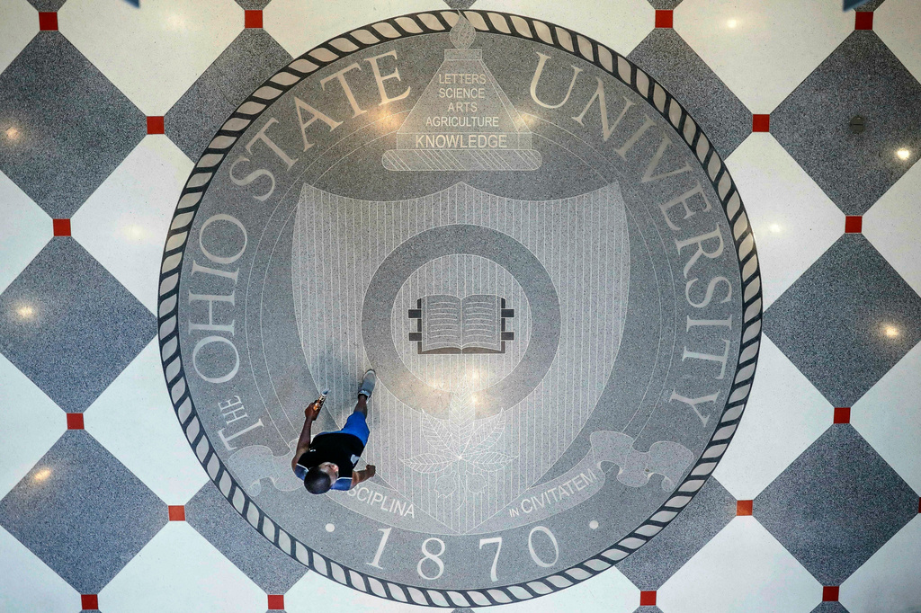 FILE - A person walks over the Ohio State University's emblem in the campus student union, May 18, 2019, in Columbus, Ohio. (AP Photo/John Minchillo, File)