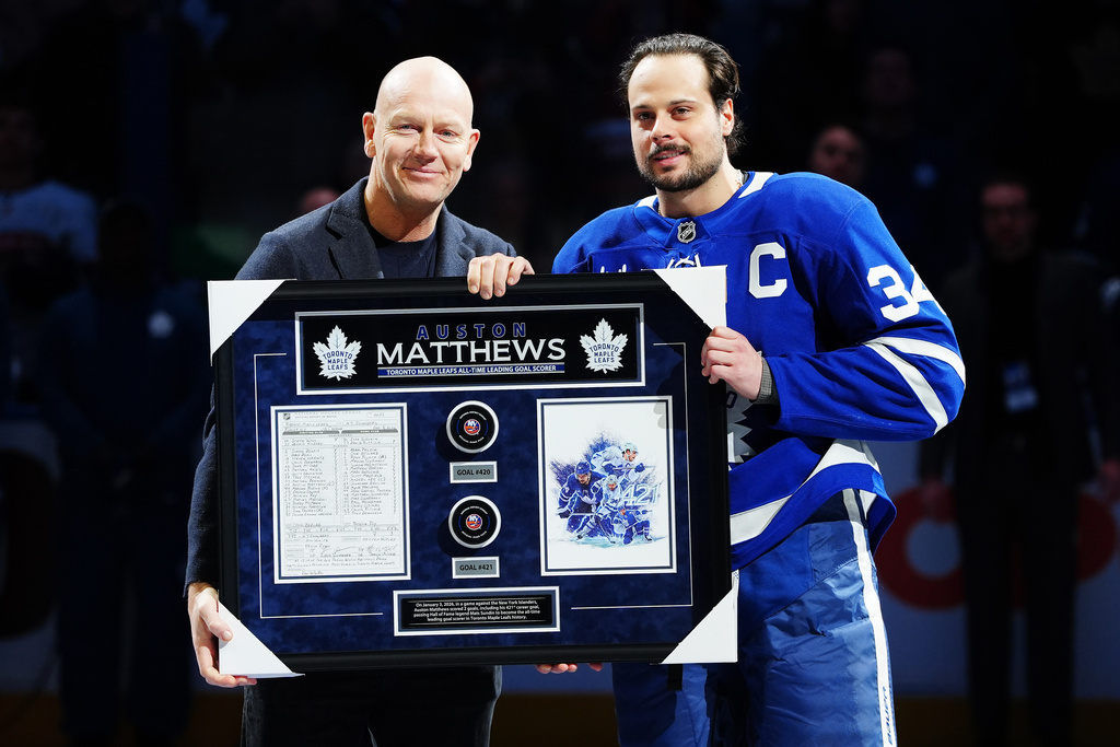 Former Toronto Maple Leafs player Mats Sundin, left, presents Auston Matthews (34) with artwork to recognize him on becoming the all-time franchise leader in goals prior to first period of an NHL hockey game against the Florida Panthers in Toronto, Tuesday, Jan. 6, 2026. (Frank Gunn/The Canadian Press via AP)