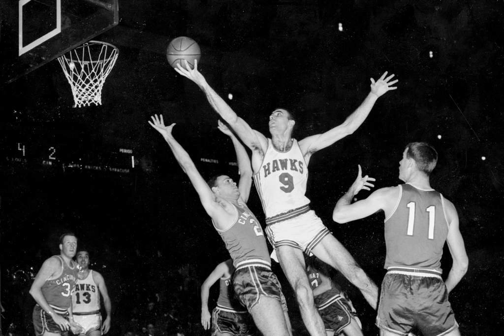 FILE - FILE - In this Dec. 10, 1957, file photo, Bob Pettit, of the St. Louis Hawks, leaps to make a one-handed shot but fails to connect for a score in the first quarter of an NBA basketball game against the Cincinnati Royals at Madison Square Garden in New York City. Blocking Pettit is Dick Ricketts (24) of the Royals as Jim Paxson (11) watches play. (AP Photo/File)