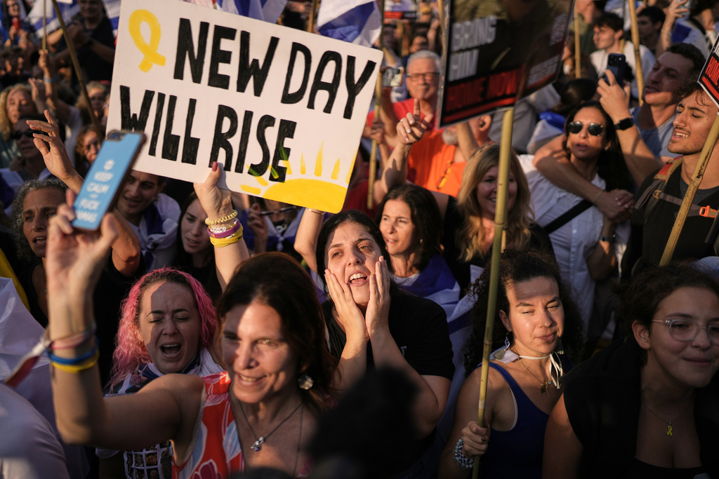 People react as they gather to watch a live broadcast of Israeli hostages released from Gaza at a plaza known as hostages square in Tel Aviv, Israel, Monday, Oct. 13, 2025. The release took place as part of a cease-fire agreement between Israel and Hamas. (AP Photo/Oded Balilty)