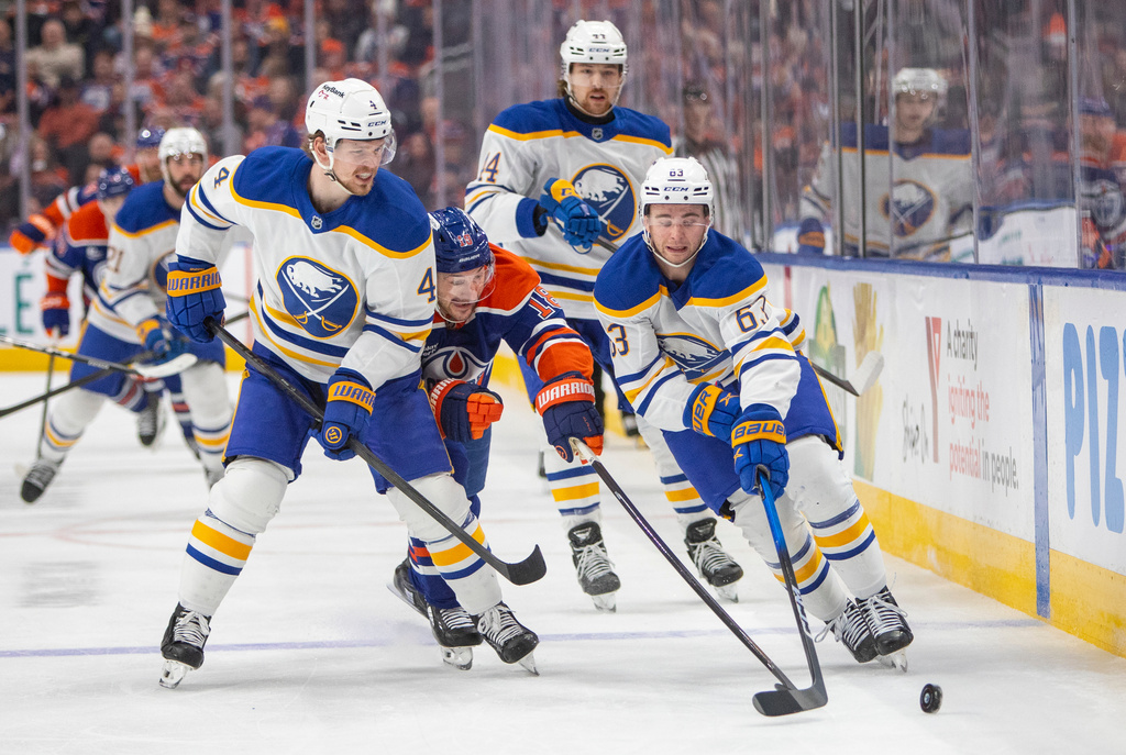 Buffalo Sabres \b63\, Bowen Byram (4) and Josh Dunne (44) outmaneuver Edmonton Oilers Zach Hyman (18) during second period NHL action in Edmonton, Tuesday, Dec. 9, 2025. (Amber Bracken/The Canadian Press via AP)