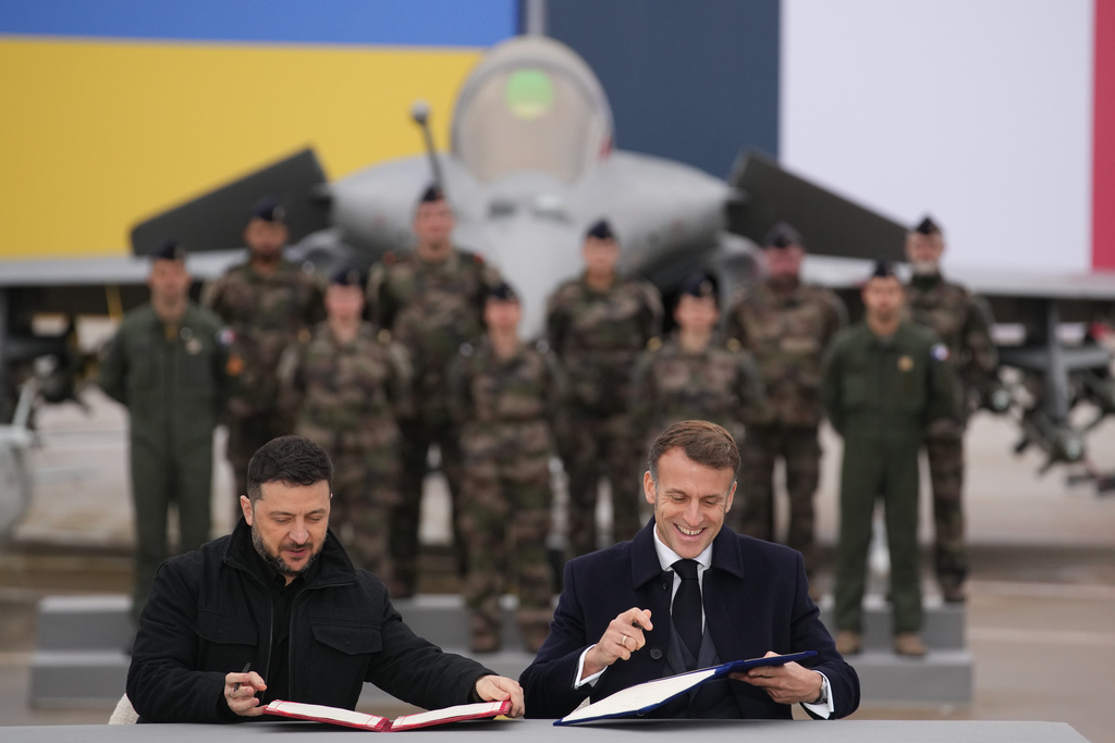French President Emmanuel Macron, right, and Ukrainian President Volodymyr Zelenskyy sign an agreement Monday, Nov. 17, 2025 at the Villacoublay air base near Paris. (AP Photo/Christophe Ena, Pool)