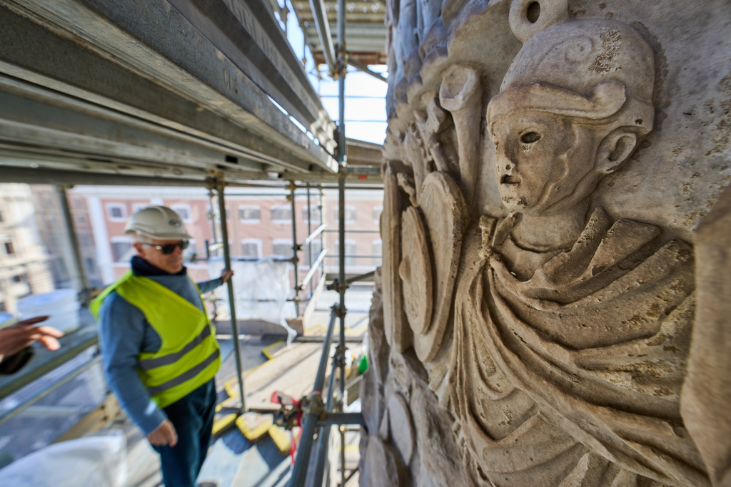 A journalist looks at bas-reliefs on the second-century A.D. Column of Marcus Aurelius in central Rome during a media tour, Thursday, Dec. 18, 2025. (AP Photo/Domenico Stinellis)