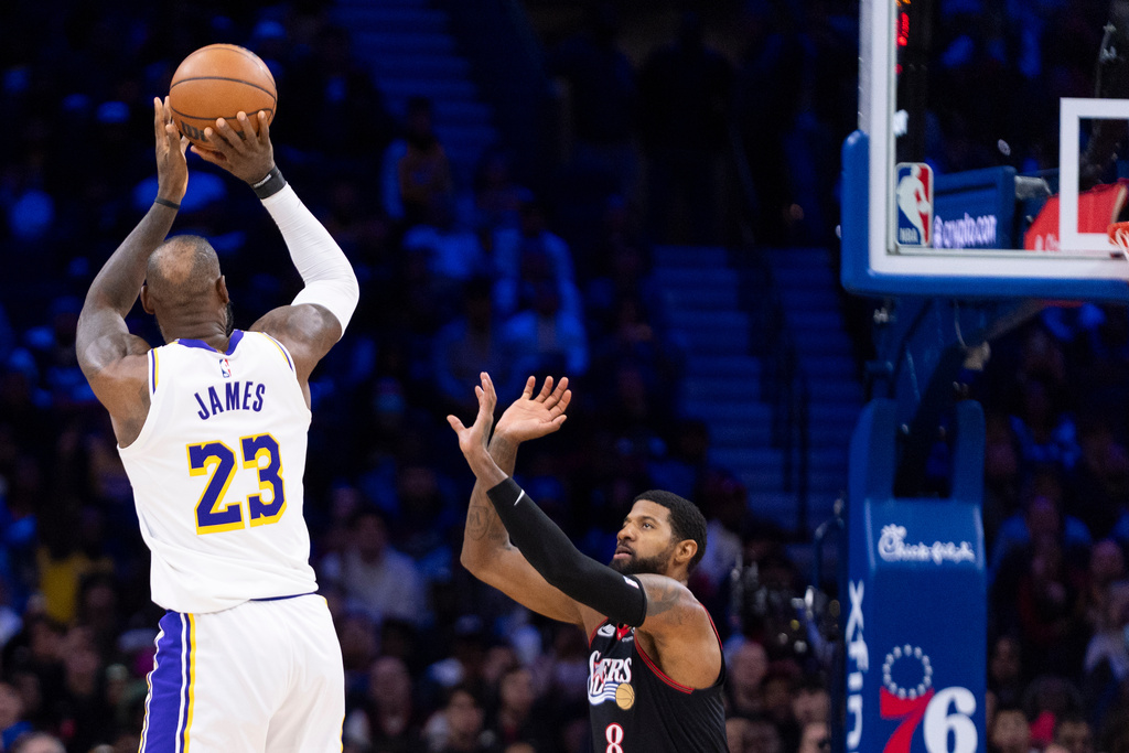 Los Angeles Lakers' LeBron James, left, shoots the ball over Philadelphia 76ers' Paul George, right, during the second half of an NBA basketball game, Sunday, Dec. 7, 2025, in Philadelphia. (AP Photo/Chris Szagola)