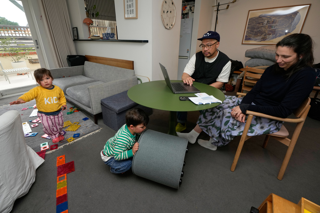 Alex, right, and Sam Lam log onto the census website in Sydney, Sunday, Aug. 9, 2026, as their 2 toddlers, Tobi and Elodie, left, play. (AP Photo/Rick Rycroft)
