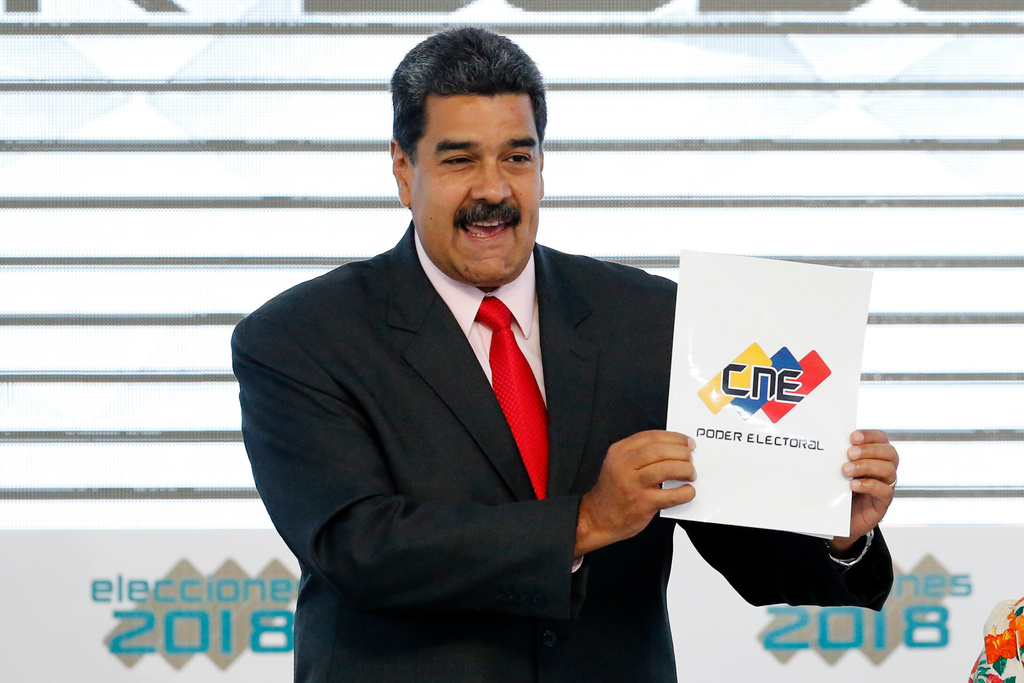 FILE - Venezuela's President Nicolas Maduro holds up the National Electoral Council certificate declaring him the winner of the presidential election, during a ceremony at CNE headquarters in Caracas, Venezuela, May 22, 2018. (AP Photo/Ariana Cubillos, File)