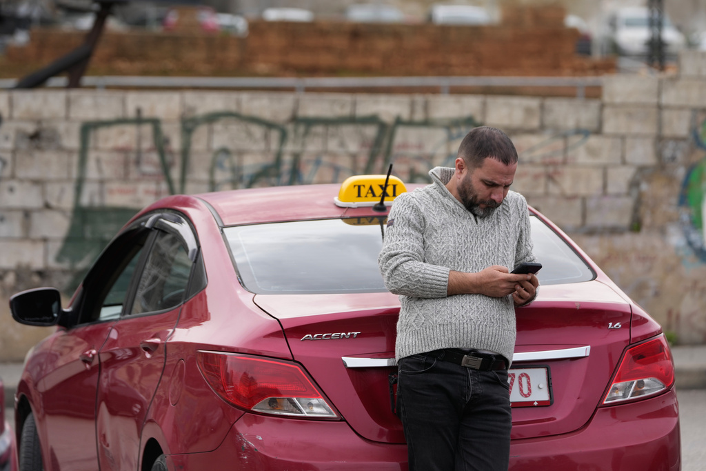A taxi driver who blocks a main highway with his car, checks his mobile phone during a protest against the increased taxes and gasoline prices issued by the Lebanese Cabinet on Monday, in Beirut, Lebanon, Tuesday, Feb. 17, 2026. (AP Photo/Hussein Malla)