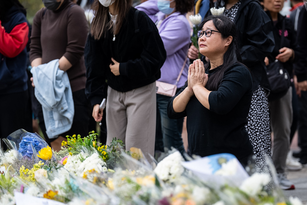 People offer flowers and pray for the victims near the site of a deadly Wednesday fire at Wang Fuk Court, a residential estate in the Tai Po district of Hong Kong's New Territories on Sunday, Nov. 30, 2025. (AP Photo/Chan Long Hei)