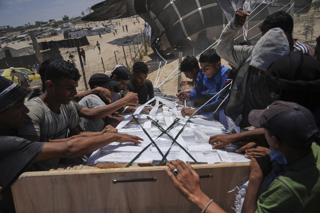 FILE - Palestinians open humanitarian aid packages that were airdropped into Deir al-Balah in central Gaza, Tuesday, Aug. 5, 2025. (AP Photo/Abdel Kareem Hana, File)