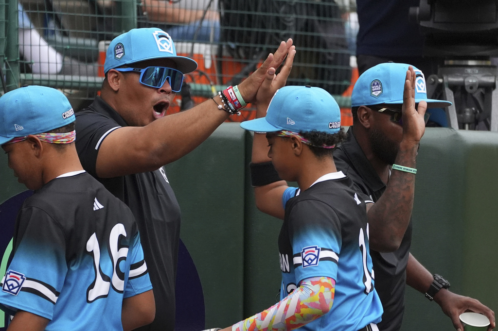 Aruba coach Maikel Trapenberg, second from left, high-fives his team following the fifth inning of a baseball game against Venezuela at the Little League World Series, Thursday, Aug. 21, 2025, in South Williamsport, Pa. (AP Photo/Caleb Craig)