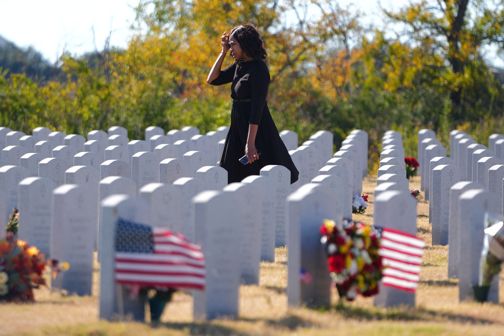 A women walks among grave stones the Dallas-Fort Worth National Cemetery where the upcoming annual Veterans Day program has been canceled due to the federal government shutdown in Dallas, Tuesday, Nov. 4, 2025. (AP Photo/LM Otero)