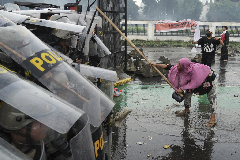A protester attacks riot police with a bamboo pole during a protest against lavish allowances given to parliament members, in Jakarta, Indonesia, Thursday, Aug. 28, 2025. (AP Photo/Tatan Syuflana)
