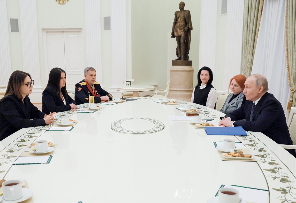 Russian President Vladimir Putin speaks to widows of Russian fallen servicemen during a military action in Ukraine, as Admiral Igor Kostyukov, head of Russian military intelligence (GRU), third left, attends a meeting at the Kremlin in Moscow, on Monday, Feb. 23, 2026. (Mikhail Metzel, Sputnik, Kremlin Pool Photo via AP)
