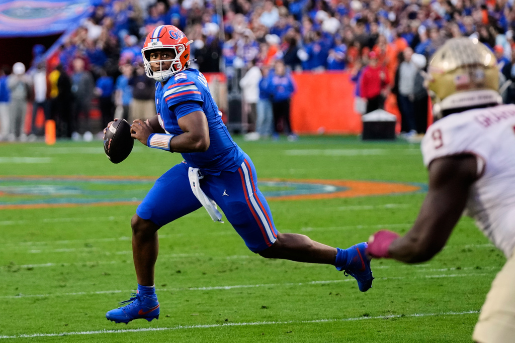 Florida quarterback DJ Lagway, left, looks for a receiver as he runs past Florida State linebacker Omar Graham Jr. (9) during the first half of an NCAA college football game, Saturday, Nov. 29, 2025, in Gainesville, Fla. (AP Photo/John Raoux)