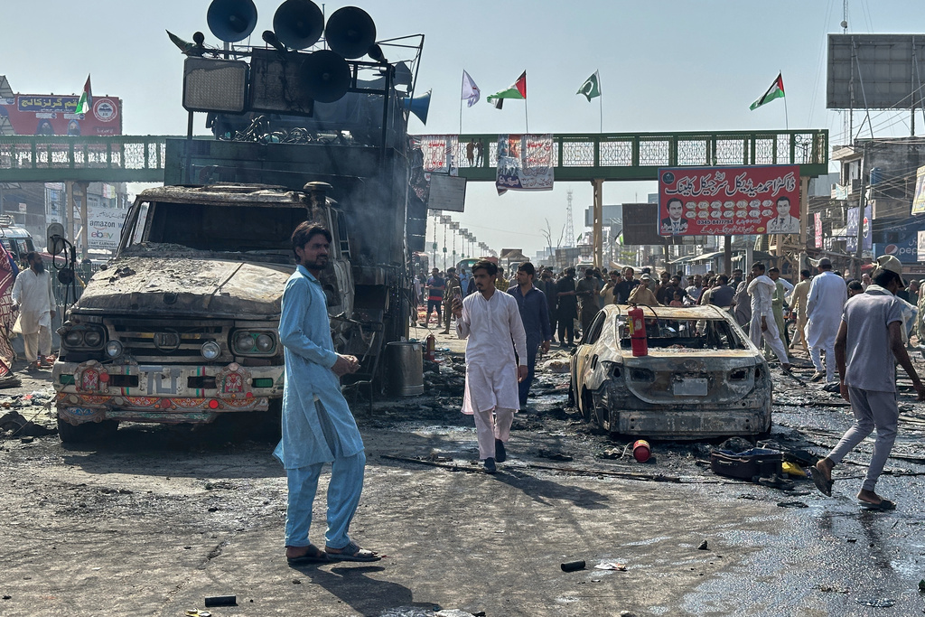 Local residents stand by burnt vehicles after police in Pakistan clashed with thousands of protesters during a march in support of Palestinians, in Muridke near Lahore, Pakistan, Monday, Oct. 13, 2025. (AP Photo/Jahanzeb Khan)